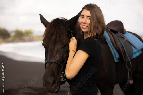 Portrait of happy woman and brown horse. Young Caucasian woman hugging horse. Romantic concept. Love to animals. Nature concept. Bali © Olga