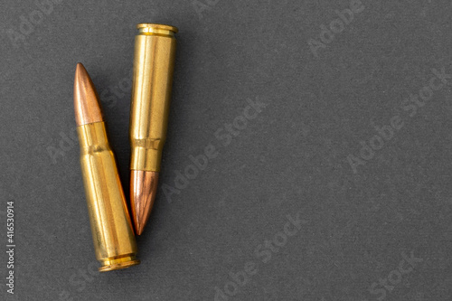 Two bullets on gray paper background. Cartridges 7.62 caliber for Kalashnikov assault rifle, closeup with copy space