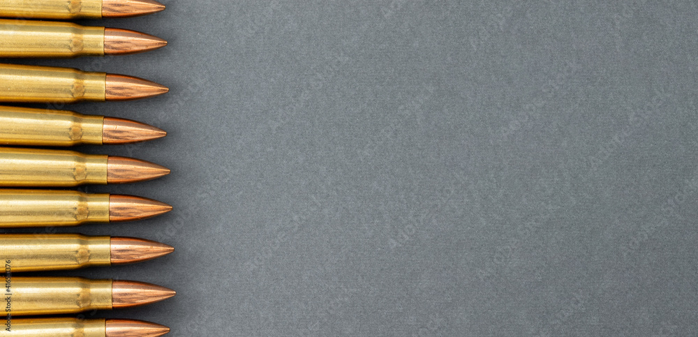 Bullets on gray paper background. Cartridges 7.62 caliber for Kalashnikov assault rifle, closeup wide banner with copy space