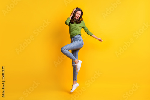Fototapeta Naklejka Na Ścianę i Meble -  Full size photo of gorgeous active young woman wear jeans touch hair jump up isolated on vibrant yellow color background