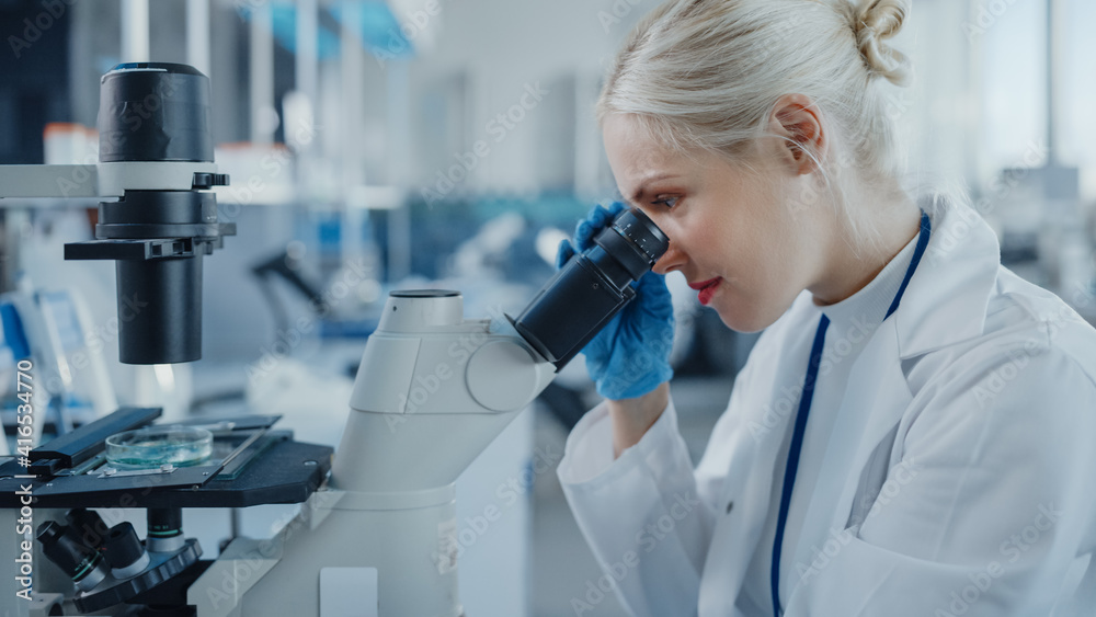 Modern Medical Research Laboratory: Portrait of Female Scientist Looking Under Microscope, Analysing Biochemicals Samples. Advanced Scientific Lab for Medicine, Microbiology Development Modern Medical Research Laboratory: Portrait of Female Scientist Looking Under Microscope, Analysing Biochemicals Samples. Advanced Scientific Lab for Medicine, Microbiology Development