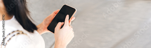 Woman hand holding a smart phone at outdoor and touching text a message chat.