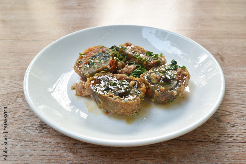 slice boiled  black preserved egg dressing spicy fried chop pork and basil leaf on plate