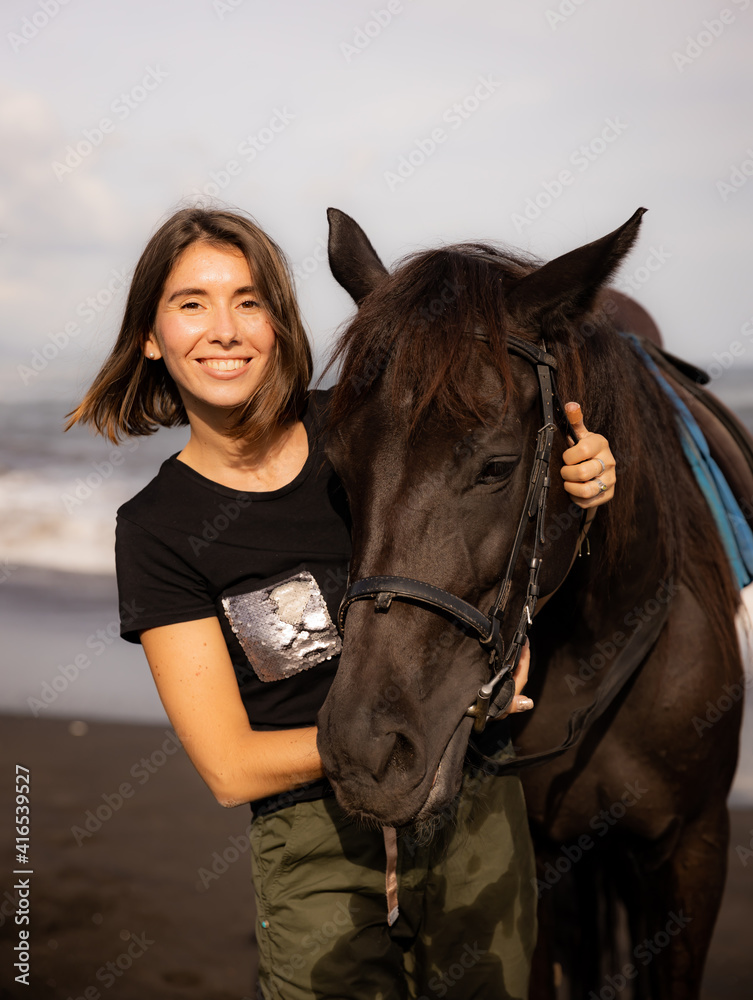 Portrait of happy woman and brown horse. Young Caucasian woman hugging horse. Romantic concept. Love to animals. Nature concept. Bali Portrait of happy woman and brown horse. Young Caucasian woman hugging horse. Romantic concept. Love to animals. Nature concept. Bali