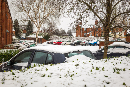 Cars parked on british street under winter snow fall in england uk