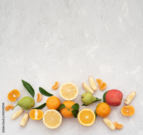 Many different fruits: tangerines, oranges, grapefruits, apples and pears on pale gray background. Fruits contain many vitamins, prepare fresh juices useful for healthy lifestyle. Close-up, horizontal © vera