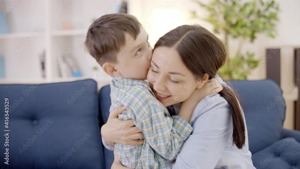 Happy son hugging young mother, kissing on the cheek, tender relationship, love Happy son hugging young mother, kissing on the cheek, tender relationship, love