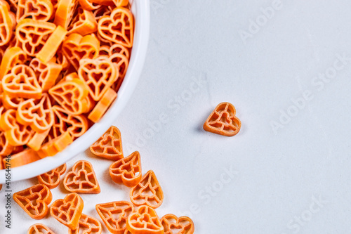 Heart shaped raw pasta in the corner of white background
