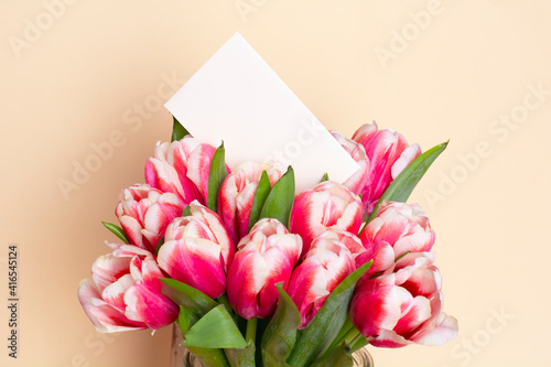 Fototapeta Naklejka Na Ścianę i Meble -  Bouquet of fresh red-white tulips on beige background. Gift for romantic date. Tender spring flowers. Bunch of tulips for Mother's Day, March 8