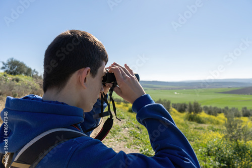 Young boy in the countryside looking the landscape using binoculars.