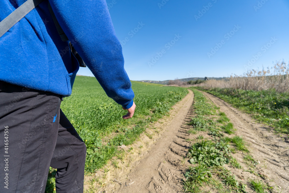 Fototapeta premium Unrecognized young boy wearing sports clothes and backpack walking in the countryside. Selective focus.