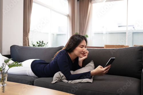 Happy young asian woman using mobile phone talking with friends on cell phone