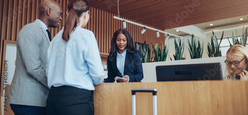 African American concierge checking in two smiling hotel guests