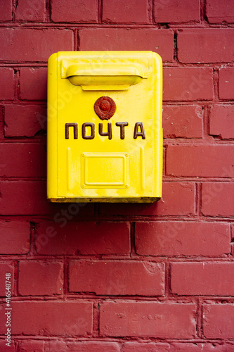 Vintage yellow letterbox from Soviet times on brown brick wall