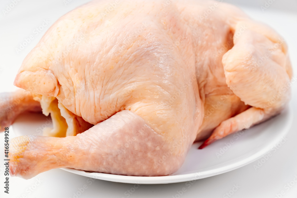 carcass of raw chicken on a white plate on a white background. carcass of raw chicken on a white plate on a white background.