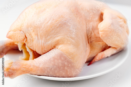 carcass of raw chicken on a white plate on a white background. 