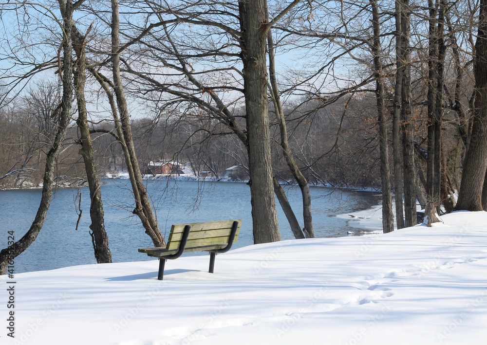 A bench with a view of the river on a snowy day.