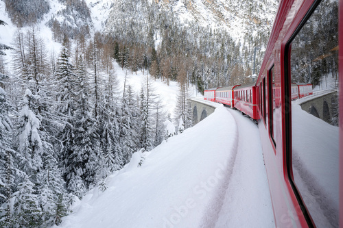 Bernina Express train in the alpine landscape covered with snow, Preda Bergun, Albula Valley, Graubunden Canton, Switzerland, Europe photo