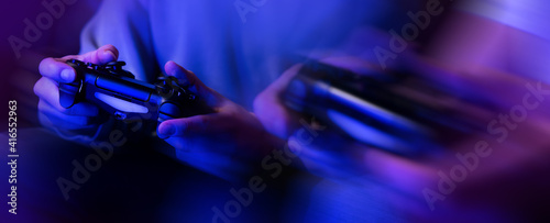 gamers playing console video games. controller in hands closeup. neon lights banner photo