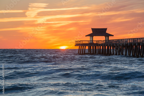 View across the Gulf of Mexico from beach beside Naples Pier, sunset, golden sky above horizon, Naples, Florida, United States of America, North America