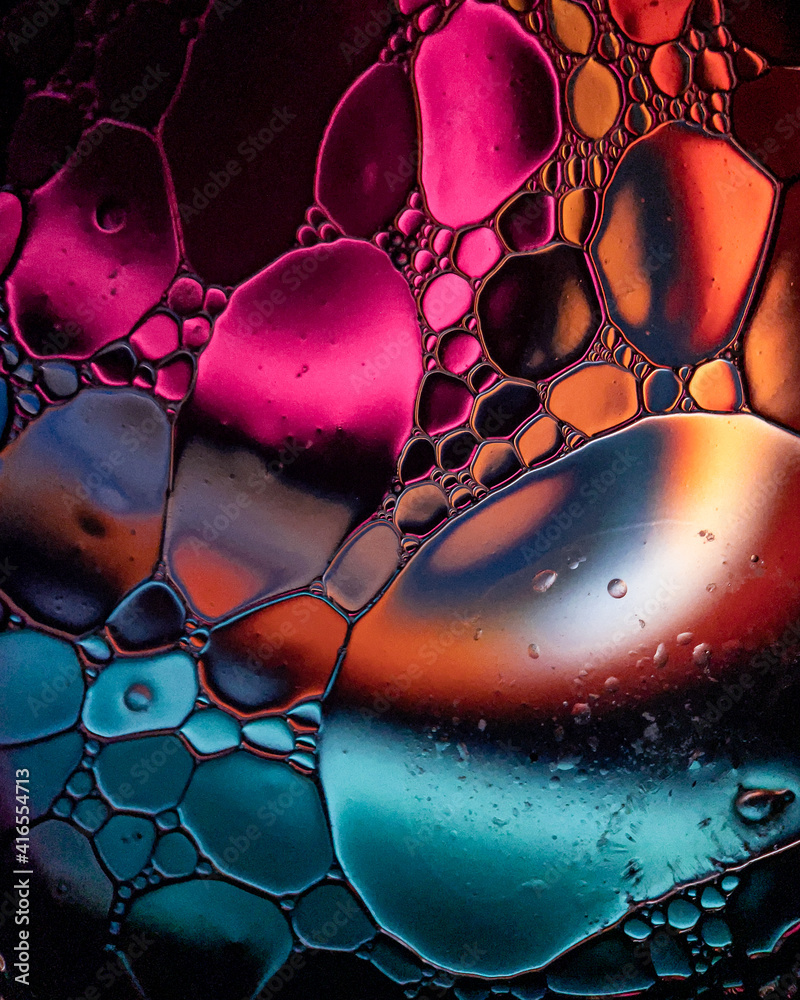 Oil drops on a water surface abstract with an aqua blue and pink swirl background