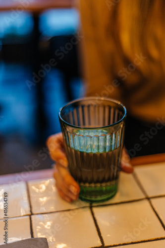 Woman holding a clear glass of water close up in a restaurant