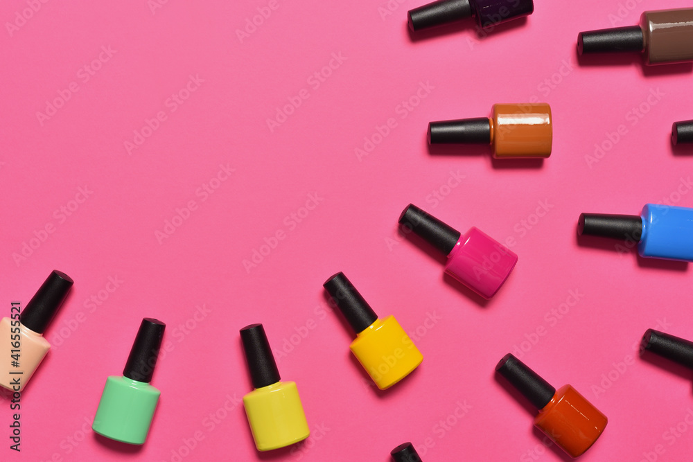 Obraz premium Bottles of nail polish on pink background top view with text space