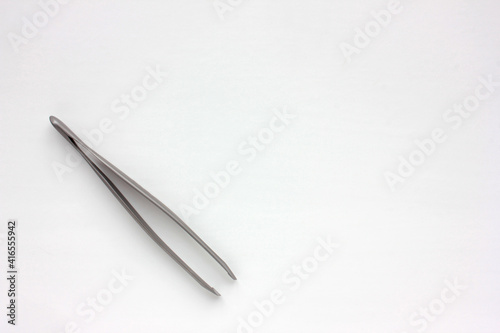 Eyebrow tweezer on a white background. Beauty and care concept. Top view, copy space. 
