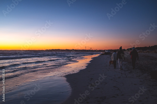People walking on the beach during the sunset