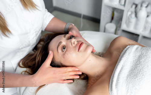 Facial massage of young woman receiving spa massage in beauty spa. Cosmetology.