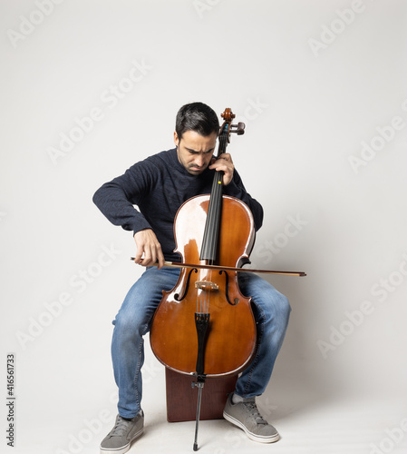 Leinwand Poster young man playing cello on the white background
