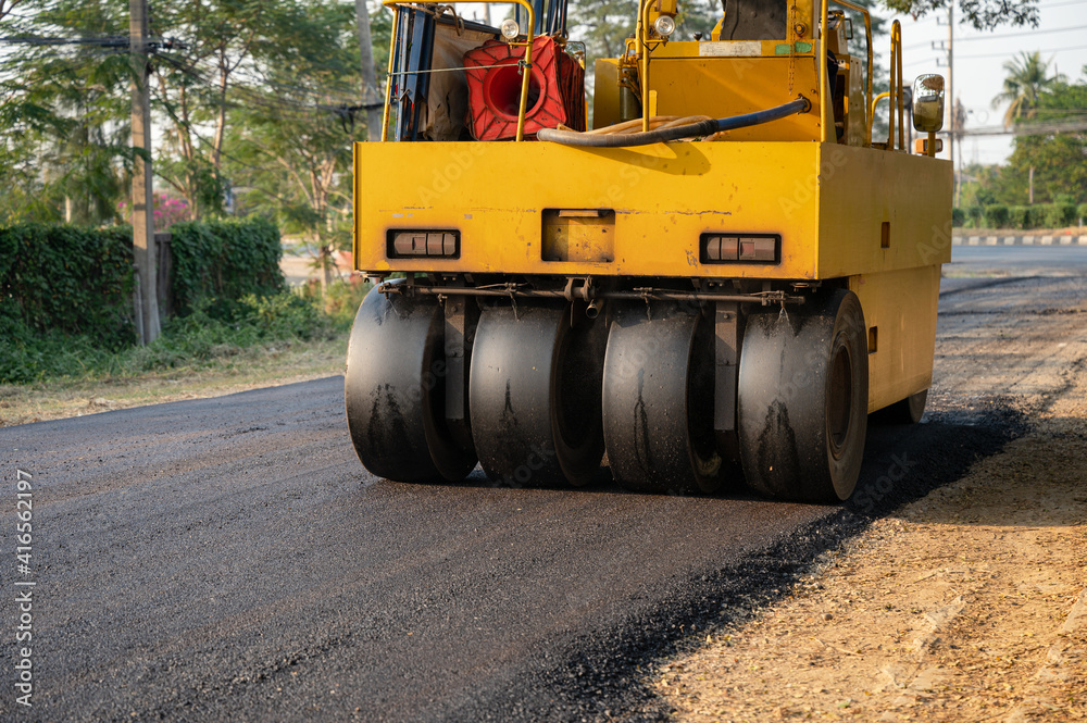Heavy vibration yellow steamroller or soil compactor working on hot-mix asphalt pavement road