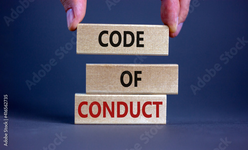 Code of conduct symbol. Concept words 'Code of conduct' on wooden blocks on a beautiful grey background. Businessman hand. Business and code of conduct concept. Copy space. photo