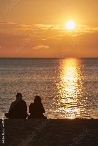 People are watching a romantic sunrise on the sandy beach of the Baltic Sea in Sopot