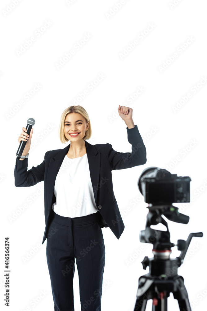 excited newscaster showing win gesture near digital camera on blurred foreground isolated on white excited newscaster showing win gesture near digital camera on blurred foreground isolated on white