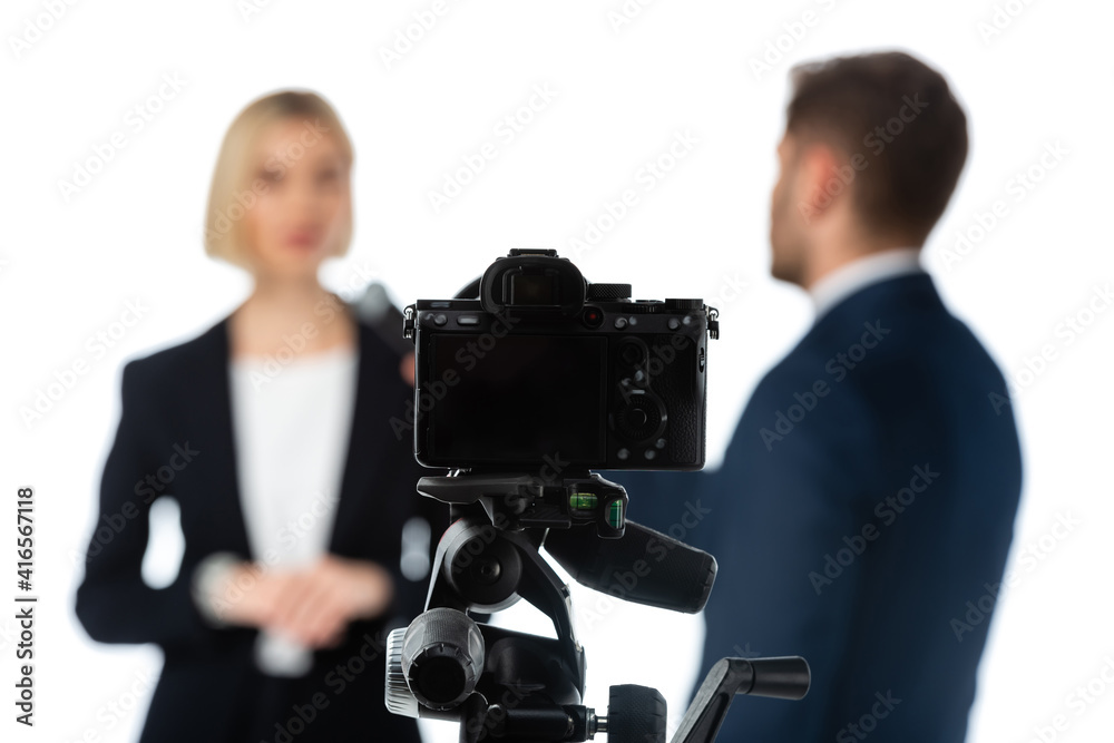 selective focus of digital camera near couple of news anchors on blurred background isolated on white