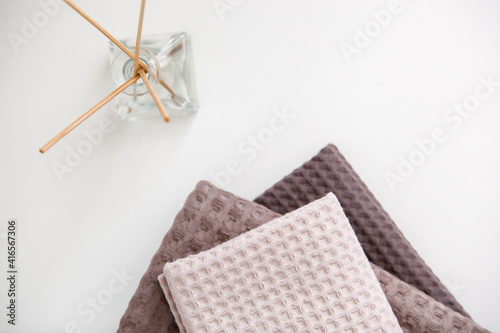 expensive luxury towels in beige and brown tones on a white background, glass aroma diffuser. photo in light colors. cleanliness and relaxation.