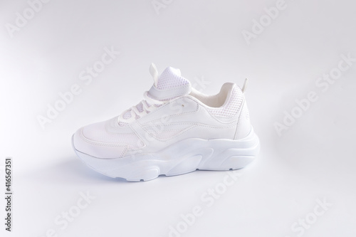 one white sporty shoes on light background, side view of white sneakers