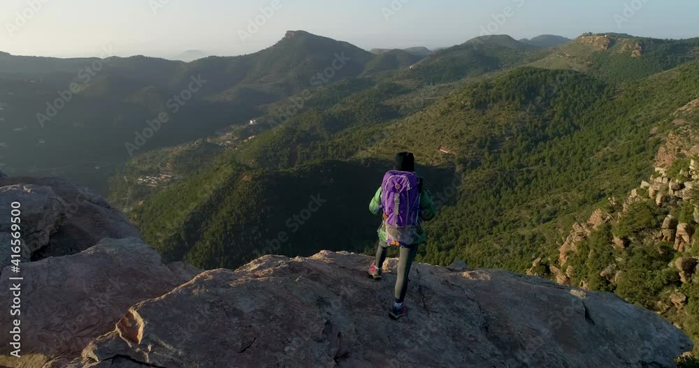 dron orbitando a una mujer escaladora con mochila de pie al borde del precipicio dron orbitando a una mujer escaladora con mochila de pie al borde del precipicio