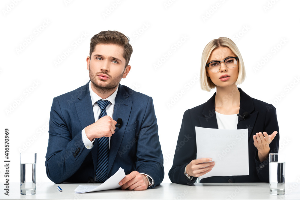 displeased news anchor holding paper and pointing with hand near colleague isolated on white displeased news anchor holding paper and pointing with hand near colleague isolated on white