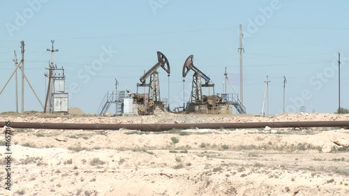 A rocking rod pump pumps oil in the desert.