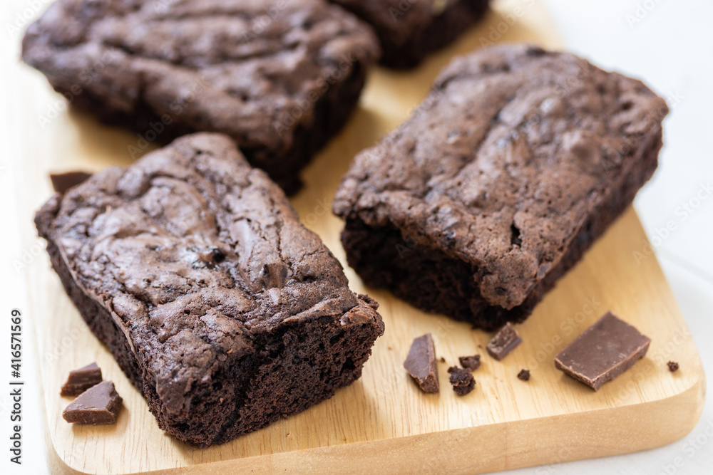 Top view of chocolate brownies on wooden board on white table, homemade sweet and dessert concept Top view of chocolate brownies on wooden board on white table, homemade sweet and dessert concept