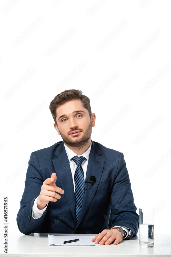 young news commentator pointing with finger near papers and glass of water isolated on white young news commentator pointing with finger near papers and glass of water isolated on white