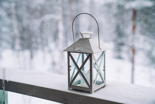 Lantern, flowers pot covered with the snow on a terrace on the snowy and frosty forest background. Selective focus. © eskstock