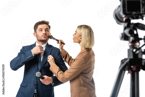 broadcaster adjusting tie while makeup artist powdering his face isolated on white, blurred foreground photo