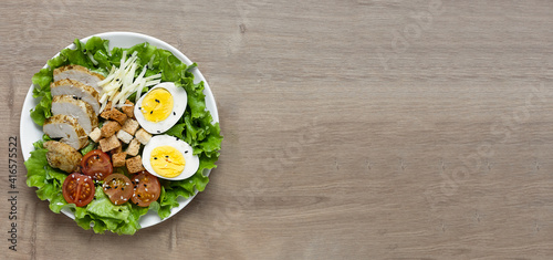 Caesar salad with fried chicken, fresh tomatoes, croutons, lettuce, parmesan cheese and eggs. Healthy eating. Top view. Banner. Copy space