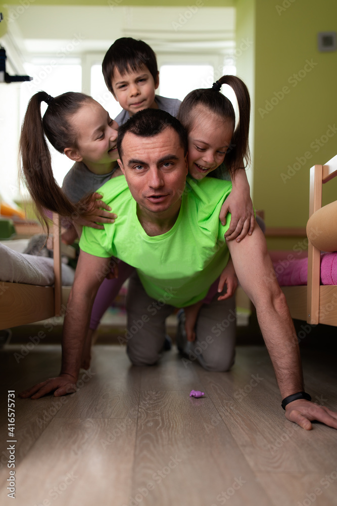 Father having fun with three children carrying them on his back at home