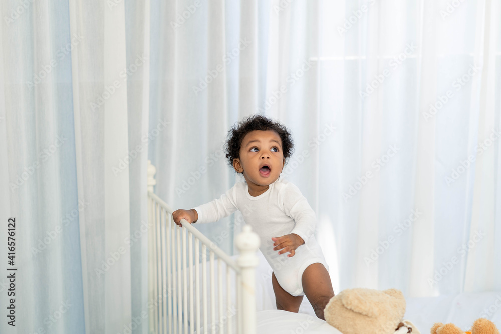 Happy African American Little baby boy climb the head of the bed and looking for some thing to learn