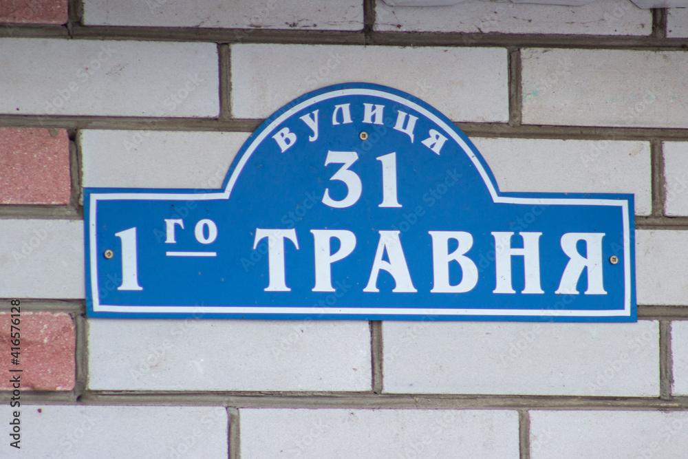 A sign on a blue house. Brick wall.