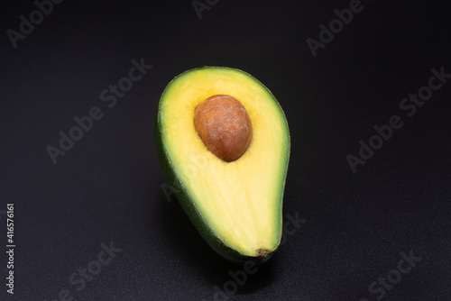 Obraz na płótnie Half an avocado with a bone on a black background w salonie